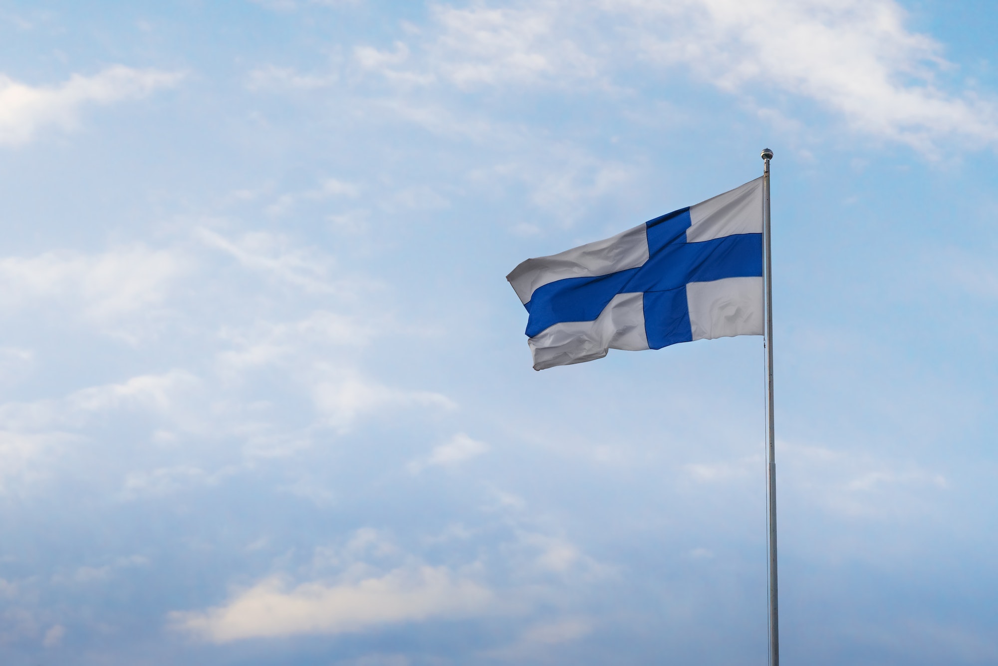 Finnish Flag - National Flag of Finland on a blue sky - Helsinki, Finland